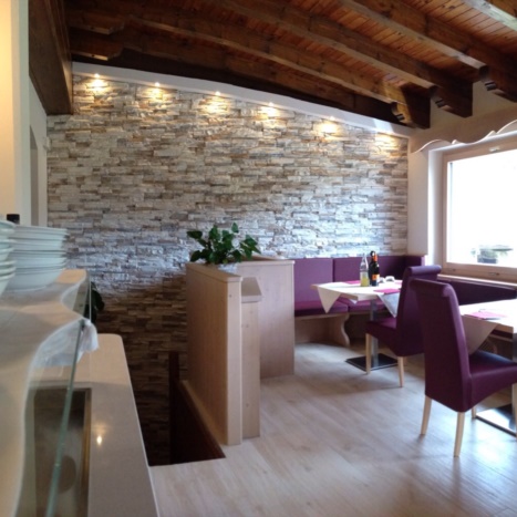 Sala da pranzo con parete in Geopietra e piastrelle effetto legno. 